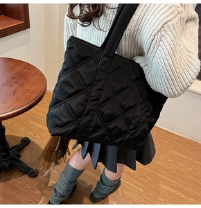 Dettaglio di una borsa tote nera trapuntata con cuciture a rombi in un contesto reale