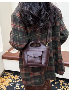 Detail of dark brown vintage leather bucket bag styled with a stylish checkered autumn coat
