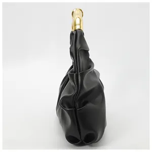 Detail of ruched black cloud bag with a curved metallic gold handle for evening wear