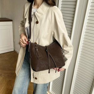 Minimalist brown leather tote bag with FASHION tag worn with a beige trench coat