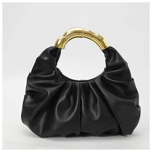 Detail of ruched black cloud handbag with decorative golden metal bamboo handle