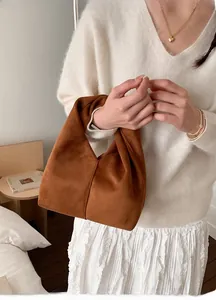Detailed view of caramel suede hobo bag with pleated texture held by a female model