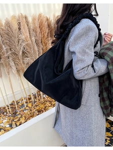 Detail of black large capacity hobo bag with unique ruched cloud strap on autumn coat