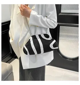 Close-up of black and white striped knit shell bag with elegant silver metal chain