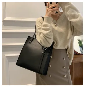 Detail of black leather tote bag featuring a silver ring buckle and decorative strap