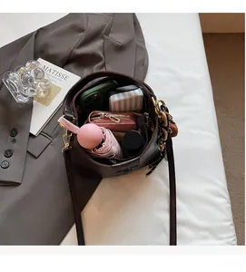 Top view of spacious brown bucket bag interior holding a phone, wallet, and umbrella