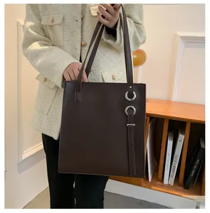 Detail view of large dark brown tote bag with silver rings and hanging straps shown on model