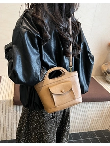 Model wearing a retro khaki bucket bag with cutout handle in a minimalist interior