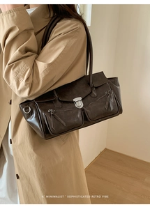 Close-up of retro dark brown leather handbag featuring silver metal buckle and zip pockets