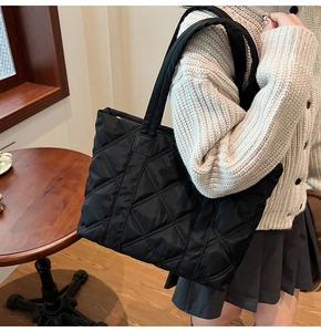 Detailed close-up of a black quilted nylon tote bag featuring spacious diamond stitching