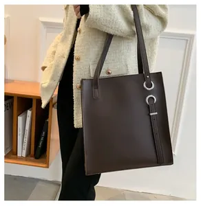 Detail of a large dark brown vintage tote bag with silver ring buckle on model