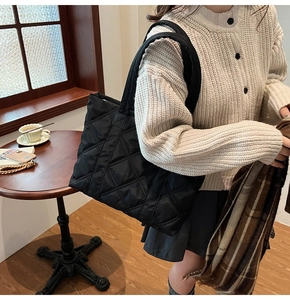 Dettaglio della borsa tote in nylon trapuntato nero con motivi a rombi in un caffè