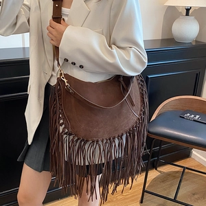 Brown suede crescent tote bag with retro fringes and adjustable strap shown on model