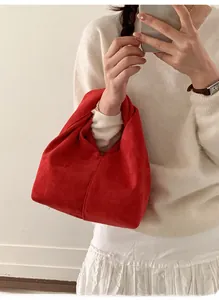 Detail view of a red suede cloud bag featuring a unique knotted handle design