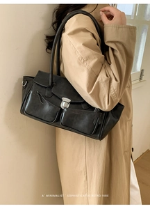 Close-up of a retro black leather shoulder bag with silver buckles and dual front pockets