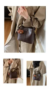 Detail of dark brown leather bucket bag with bear pendant and adjustable strap