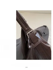Detailed shot of silver buckle hardware and textured strap on a brown tote bag