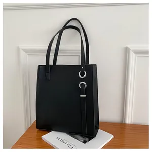 Detail of a black leather tote bag with silver ring hardware and leather tassel accents
