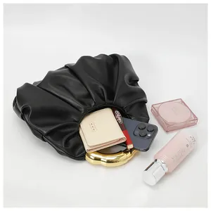 Macro shot of black pleated cloud bag capacity showing phone and makeup essentials