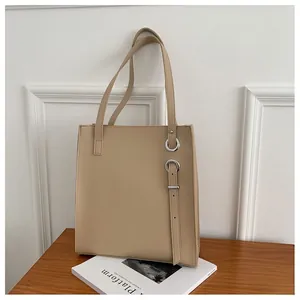 Detail of beige minimalist tote bag featuring silver hardware rings on smooth faux leather