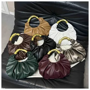 Close-up of pleated cloud bags in various colors with elegant golden metal ring handles