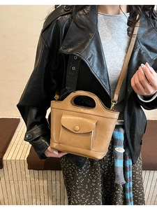 Detail of vintage brown mini bucket bag showing front pocket and top handle on a model
