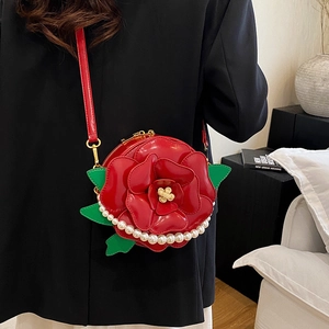 3D red rose crossbody bag with pearl trim and green leaf accents on a black blazer