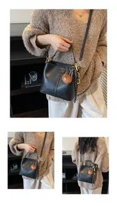 Detail of black bucket bag with lychee texture and cute bear charm and silk scarf