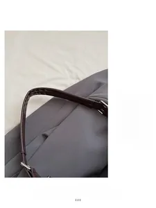 Detail of soft gray fabric texture and premium brown leather shoulder strap with stitching