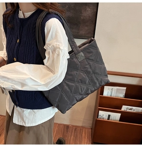 Close-up of the grey quilted tote bag with stitching detail and reinforced shoulder strap