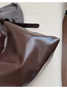 Detail of dark brown oil wax leather tote with vintage crackle texture and metal buckle