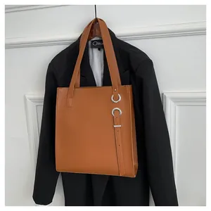Macro detail of caramel leather tote featuring silver metal rings and vertical strap