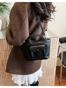 Detail view of a vintage black leather bucket bag featuring a unique cutout handle and flap pocket