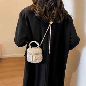 Dettaglio della borsa a scatola in tweed beige con catena dorata e manico in pelle