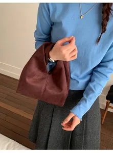 Detail of a minimalist dark brown suede cloud bag with a unique triangular silhouette