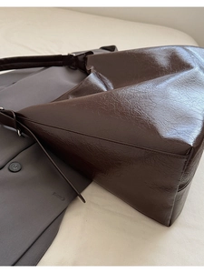 Macro detail of deep brown textured glossy leather on large commuter tote bag