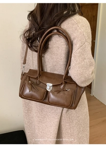 Detail of retro brown shoulder bag featuring metallic silver buckles and dual front pockets