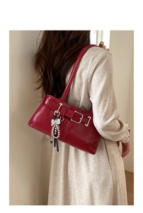 Detail view of red underarm bag with a pearl bow pendant and decorative buckle