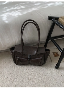 Detail of retro dark brown tote bag with two front pockets and metallic D-rings