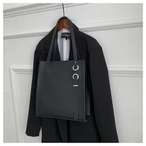 Detail of black matte leather tote bag with silver metal rings and hanging strap decoration