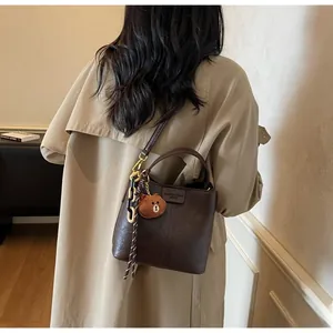 Detail of dark brown vintage bucket bag with leather tag, cute bear pendant and chain