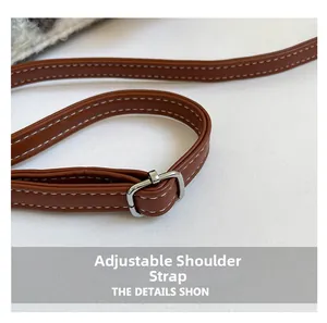 Detail of adjustable brown leather shoulder strap with white stitching and silver buckle