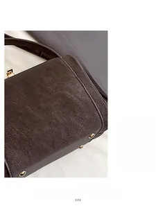 Macro shot of dark brown lychee texture leather with gold anti-wear studs on bag base