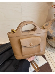 Detail of a brown PU leather bucket bag featuring a front pocket and gold-toned hardware