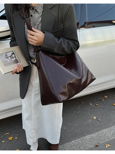 Detail of vintage chocolate brown tote bag with wrinkled leather texture in city street setting