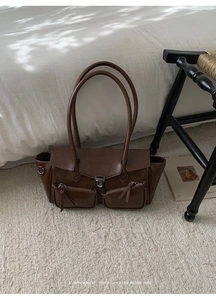 Detail of retro dark brown tote bag with zipper pockets and silver metal buckle closure