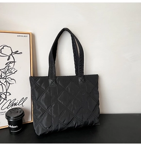 Dettaglio della texture trapuntata nera e della tracolla spessa di questa borsa tote