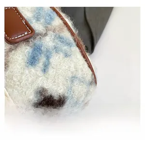 Detail of plush faux fur texture with blue and brown cow spots and red button accent