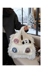 Detail of knit shoulder bag featuring colorful cartoon dog motifs and white fringe tassels