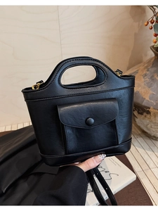Close-up of black bucket bag featuring a front flap pocket and sturdy top handle